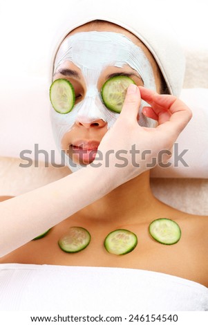 Facial mask, the woman at the beautician. Cosmetic procedure woman\'s face in the mask mitigating and cucumber slices on eyes