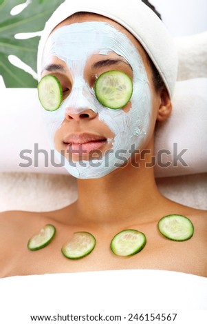 Facial mask, anti-wrinkle treatments. Cosmetic procedure woman\'s face in the mask mitigating and cucumber slices on eyes