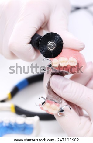 Veneers, dentures, bridges - prosthetist at work.Dentures, partial dentures.Prosthetics hands while working on the denture, false teeth, a study and a table with dental tools.
