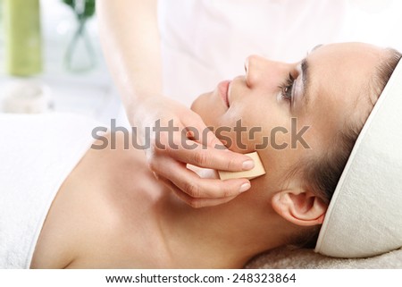 Young woman while applying makeup in the beauty salon. Woman in a beauty salon, makeup artist applied primer for face
