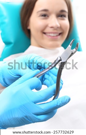 Pulling teeth. Woman at the dentist\'s chair during a dental procedure