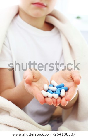 Supplements, pills help in disease. A lot of white and blue pills kept in a child\'s hand