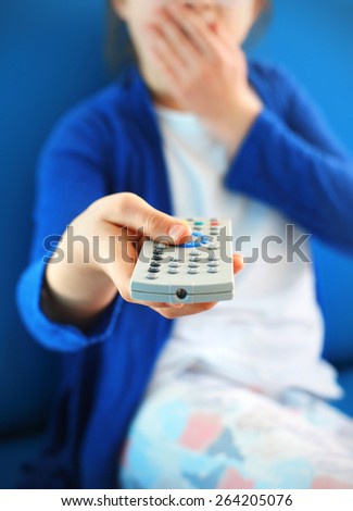 Switch off. Child with tv remote control. A teenager changes the channel on the TV using the remote control