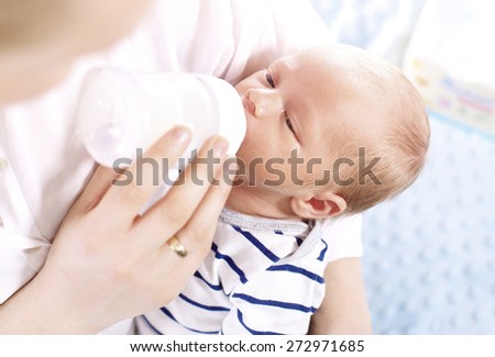 Mother is feeding newborn baby.\
A woman feeds a newborn with modified milk from a bottle