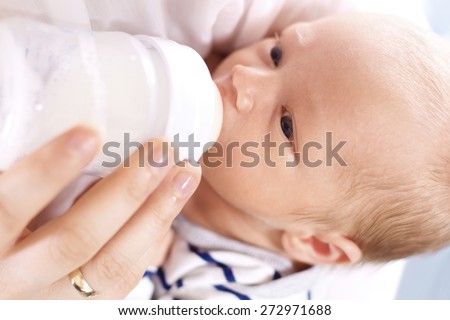 Infant nutrition.\
A woman feeds a newborn with modified milk from a bottle