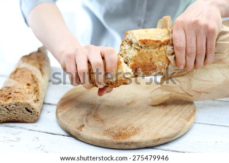 Wheat roll. Woman hands cutting bread on the kitchen counter