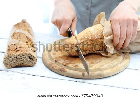 Slicing bread. Woman hands cutting bread on the kitchen counter