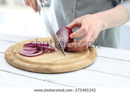 Cutting the onion into slices. Woman cut red onion