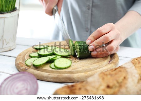 Green diet, a woman cut cucumbers. Hands woman standing in the kitchen while slicing cucumber