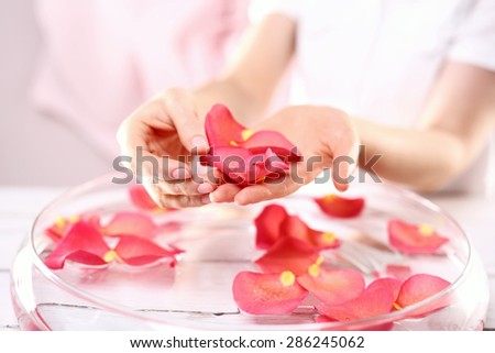 Beauty ritual for hands. Care treatment of hands and nails woman hands over the bowl with rose petals