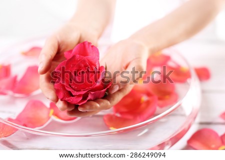 Smooth leather palm, beauty treatment clinic. Care treatment of hands and nails woman hands over the bowl with rose petals
