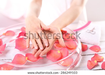 Aromatic bath hand. Care treatment of hands and nails woman hands over the bowl with rose petals