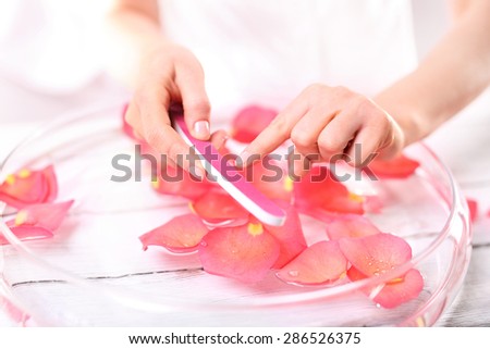Holiday manicure nails ready for summer. Woman saws nail file nails pink paper