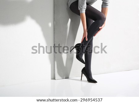 Tired legs aching, swelling. Beautiful, leggy woman in thin tights and fashionable styling
