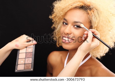 Brown eye makeup.\
Make-up artist painting a beautiful woman eyeshadows.