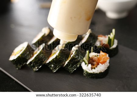 Sushi Master prepares futomaki. Classic thick rolls futomaki served on a stone plate