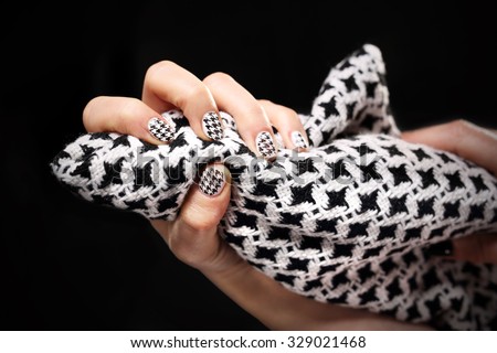 Chanel grille, black and white pattern on your nails. Woman\'s hand with fingernails painted in black and white checkered