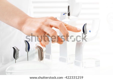Hearing aids.\
Man shows a finger on a model hearing aid