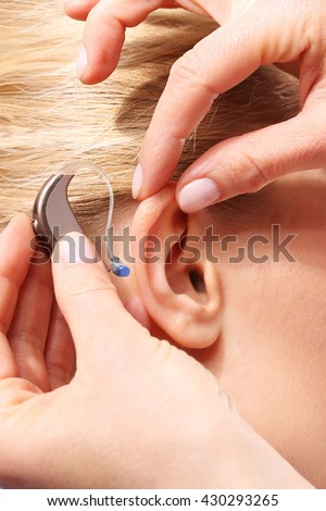 Inserting your hearing instruments. The doctor assumes the woman hearing aid in your ear