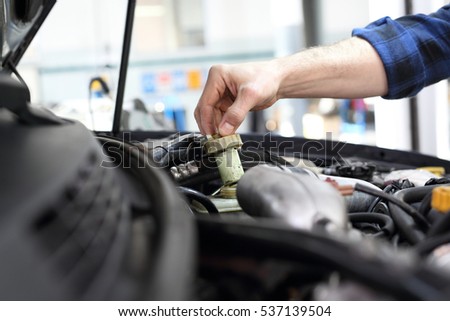 Car mechanic tightened the valve under the hood of a car.
