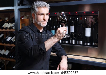 Red wine, man evaluates the color of wine in a glass. Sommelier tasting red wine
