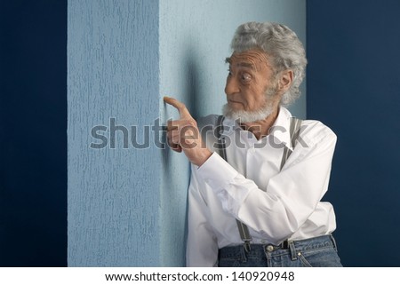 old man leaning on wall with earth based wall