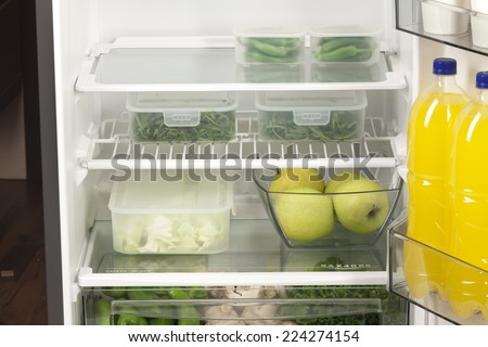Fruits and vegetables in two containers in a modern fridge - a healthy food concept.