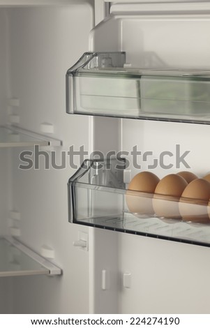 opened refrigerator full of eggs and fresh vegetables