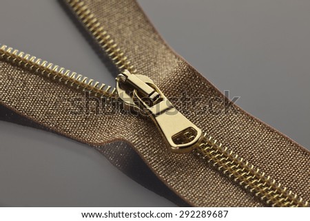 studio photography of golden brown zipper opened on a half to a gray surface