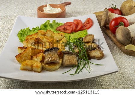 King oyster mushrooms roasted with potatoes, lettuce and tomato on the background of the ingredients