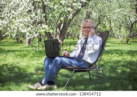 Businessman uses the Internet and running in the spring garden under the apple tree blossoms