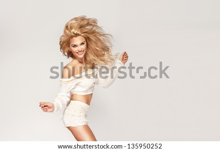 Fashionable young blonde woman jumping wearing white clothes. A lot of copy space.