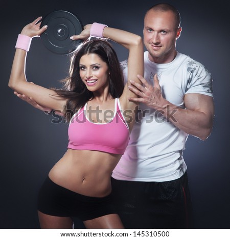 Athletic man and beautiful brunette woman doing fitness exercise, smiling, looking at camera.