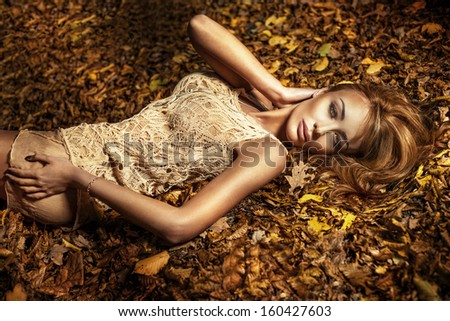 Beauty portrait of young beautiful brunette woman lying on the autumns leafs with perfect makeup.