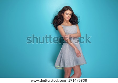 Fashionable young brunette woman posing in studio, looking at camera. Girl with long curly hair.