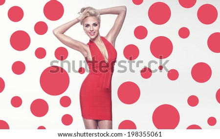 Fashionable elegant blonde woman posing in red dress, smiling.