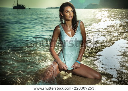 Sexy wet beautiful woman posing in sea water at sunset, Greece