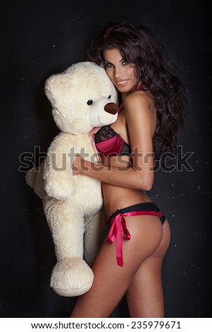 Sexy brunette woman with perfect body posing with teddy bear, smiling.