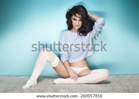 Sexy brunette woman posing in studio,sitting. Girl with long curly hair.