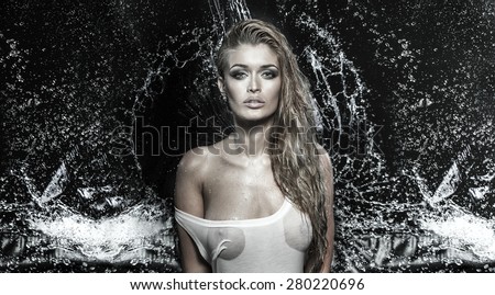 Sexy blonde woman posing wet over water drops, looking at camera.