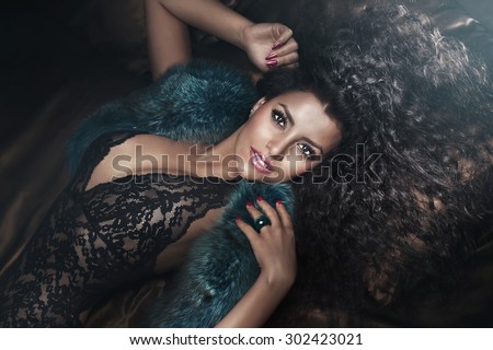 Sexy beautiful african american woman lying, looking at camera. Girl posing in sensual lingerie and fur.
