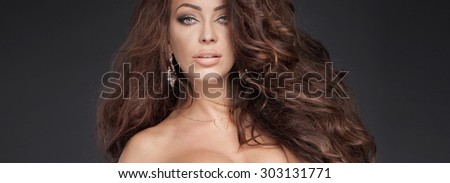 Closeup portrait of sexy brunette lady with long curly hair.