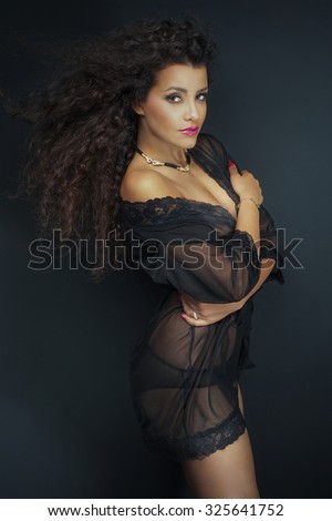 Sexy african american woman posing in black sensual lingerie. Girl with long curly hair. Studio shot.