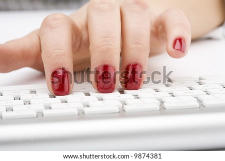 Fingers with red nail typing on keyboard