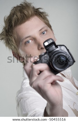 Young man holding digital photo camera on one hand