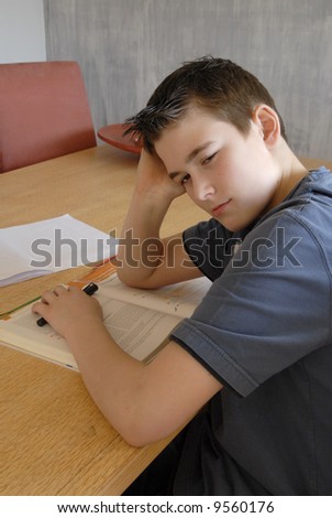 young boy doing his homework and looking fed up