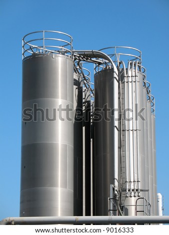 Tanks of silvery color, are photographed on a background of the blue sky
