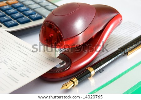Stapler of red color, pen and calculator