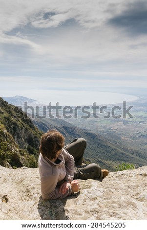 Man on top of mountain with coastline of background