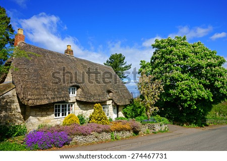 A beautiful country cottage with a thatched roof in spring time, The Cotswolds, Gloucestershire, United Kingdom